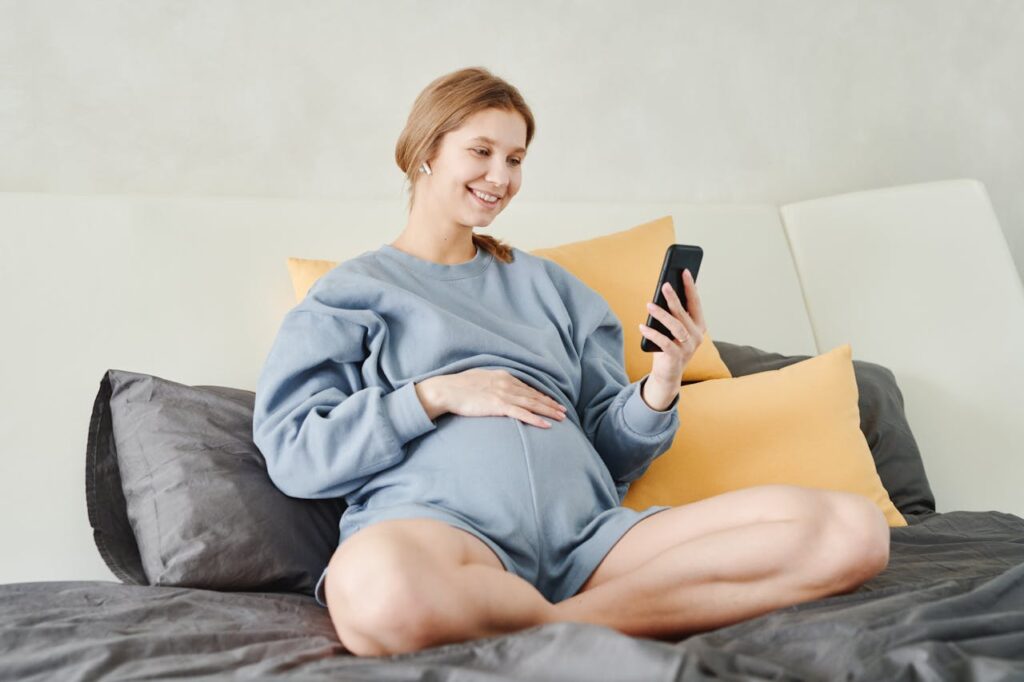 pregnant woman smiling while using her phone 