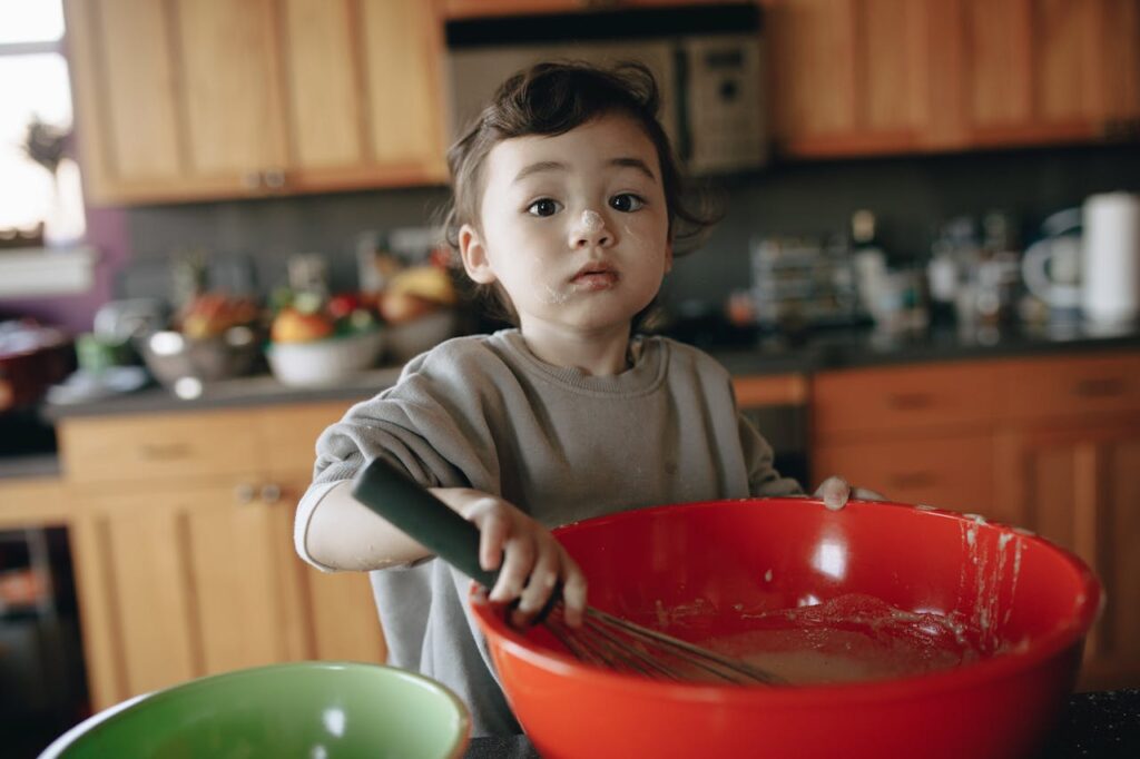 toddler whisking cake mix using a learning tower 